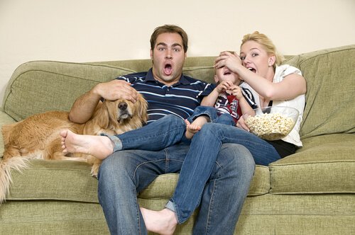 una famiglia sul sofà col cane guarda un film