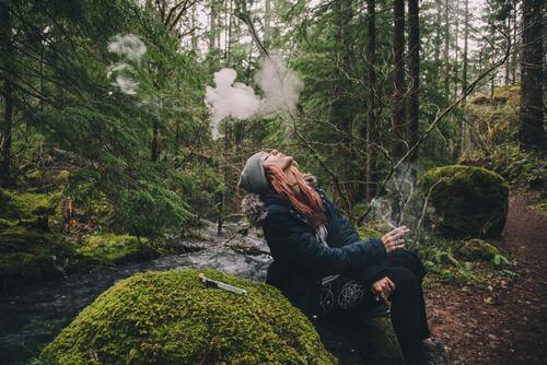 Donna che fuma nella foresta 