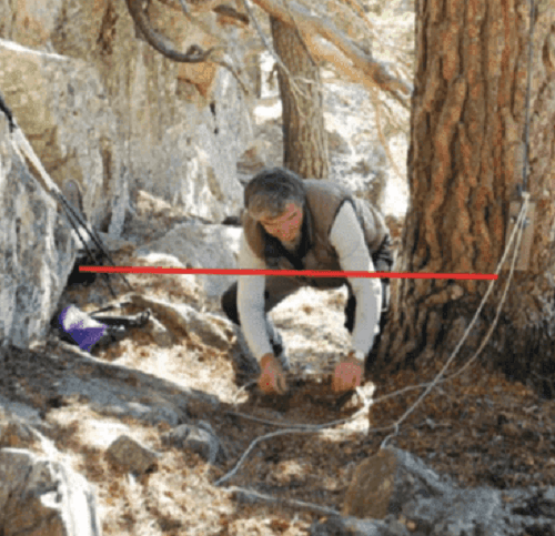 Uomo prepara una trappola per catturare un animale.