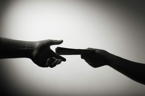 Mani che si passano un libro.